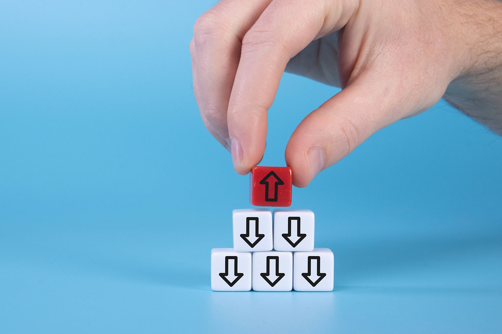 hand with white cubes with down arrows and one red cube with arrow up