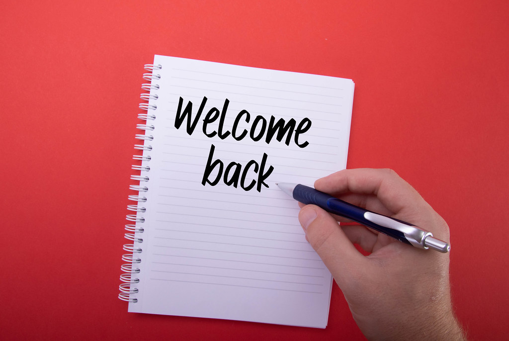 Hand writing Welcome back text in notebook on red background