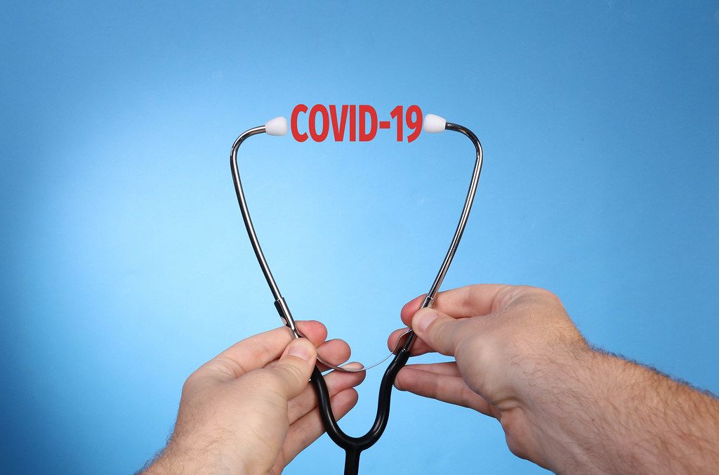 Hands holding stethoscope with Covid-19 text