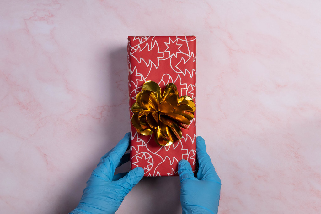 Hands in blue medical gloves holding Christmas gift box