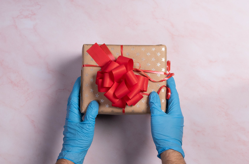 Hands in medical gloves holding Christmas gift box