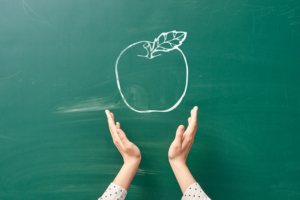 Hands of a person holds drawn on the chalkboard apple. Creative back to school concept