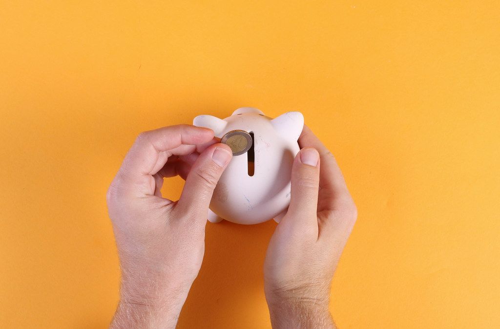 Hands putting coin into piggy bank