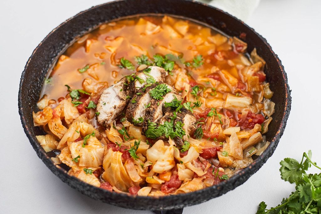 Healthy borsch soup with baked chicken meat cuts and herbs on the pan