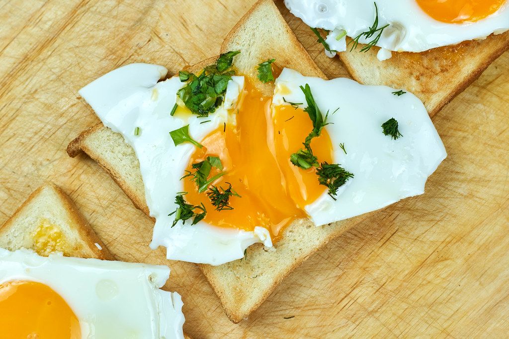 Healthy breakfast. One sunny-side-up egg with fresh herbs on a toast