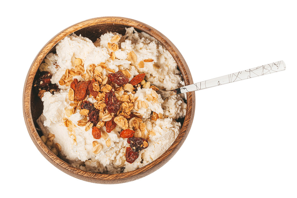 Healthy breakfast with cottage cheese, dried berries and oatmeal in a wooden bowl