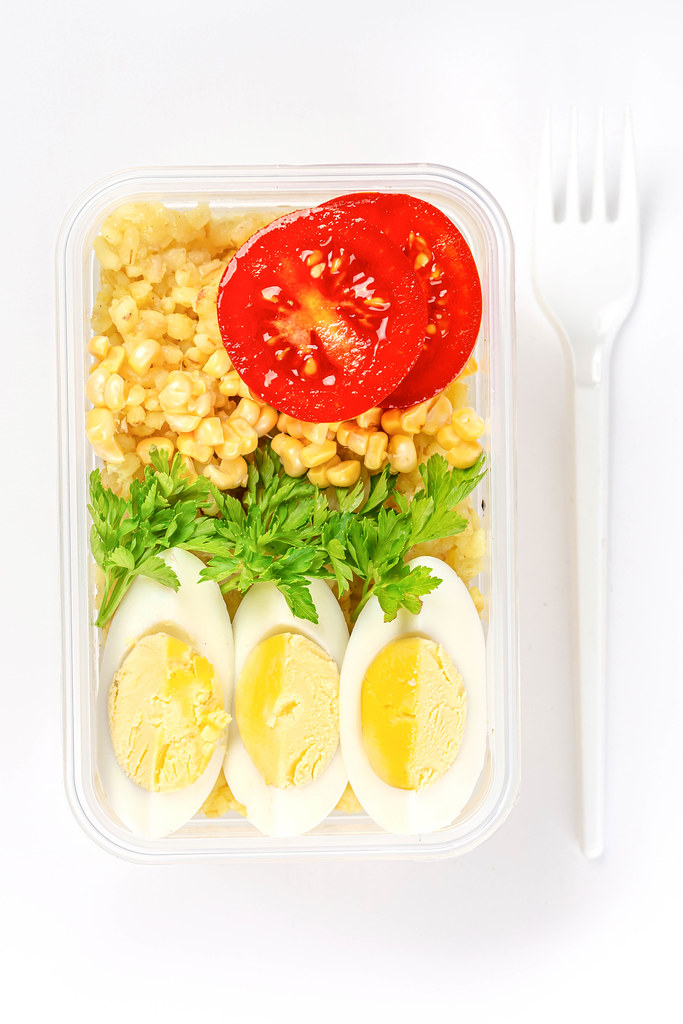 Healthy food concept: lunch box filled with bulgur, vegetables, boiled egg and parsley, top view