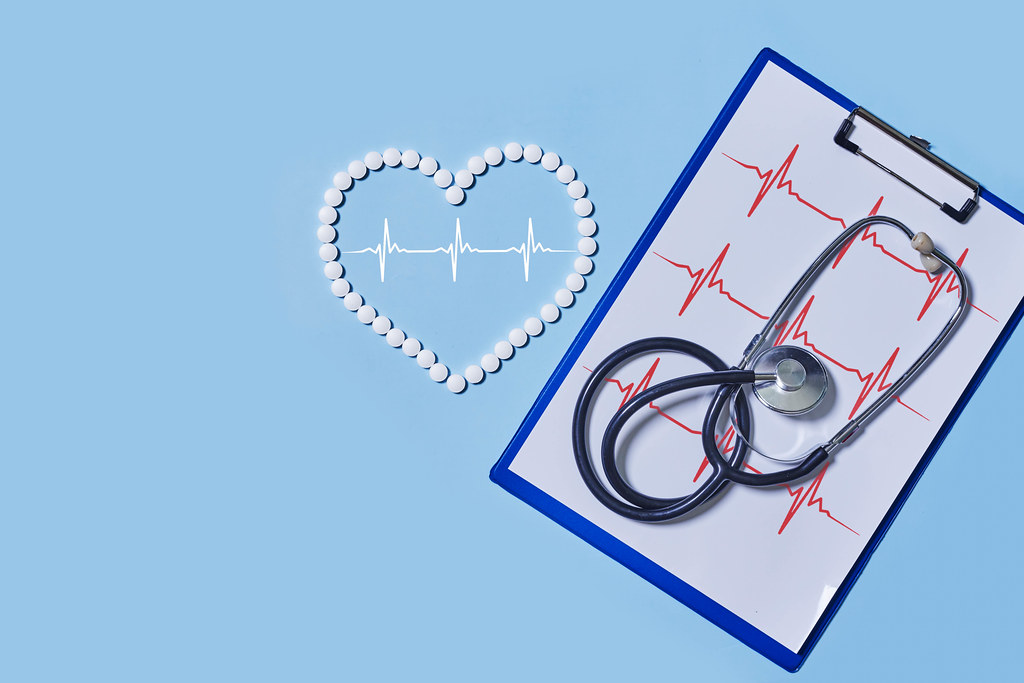 Heart ekg cardiogram, tablets and stethoscope on colored background