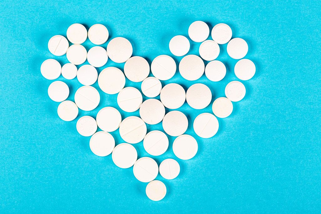 Heart made of white pills on a blue background