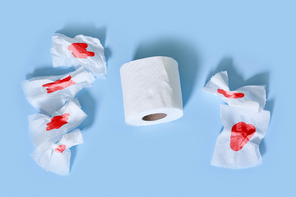 Hemorrhoid problems - sheets of toilet paper with blood on blue background