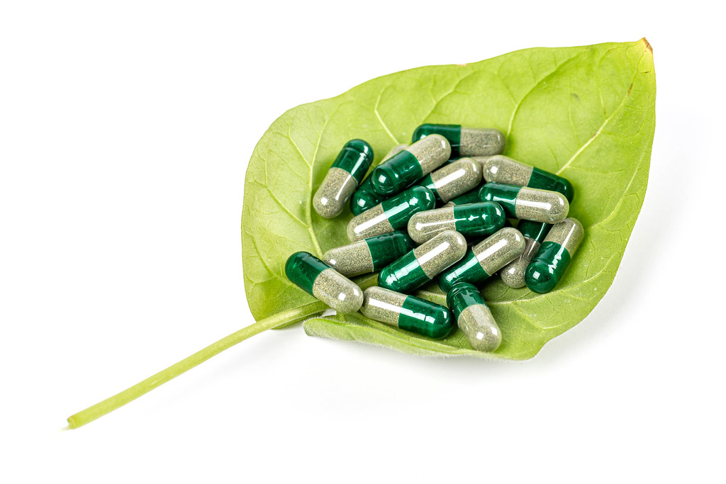 Herbal medicine capsules on green leaf