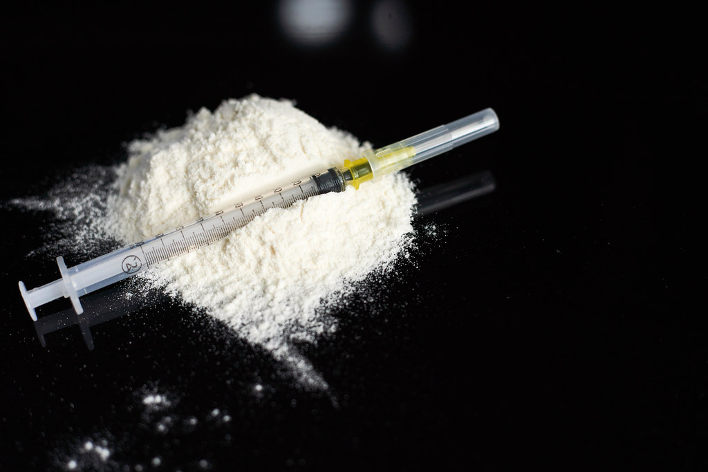 Heroin powder and syringe on black background