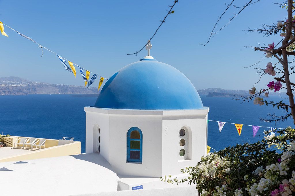 Holiday in Greece: one of the blue domes in Santorini with sea and blue sky in the background