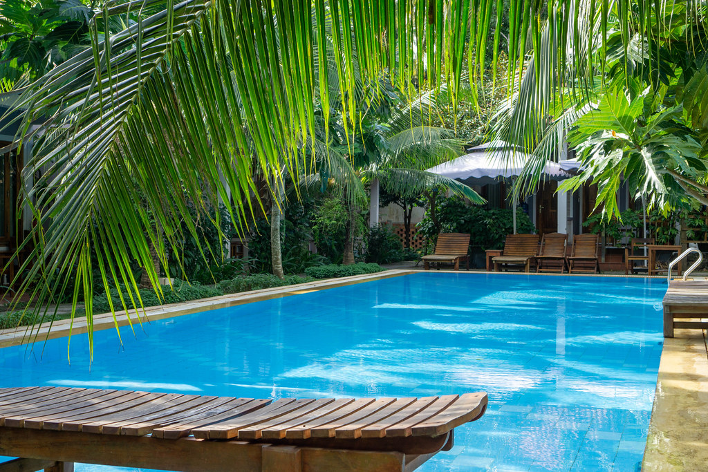 Holz-Sonnenliegen um einen Pool in einer Hotelanlage mit Villen auf der Insel Phu Quoc in Vietnam