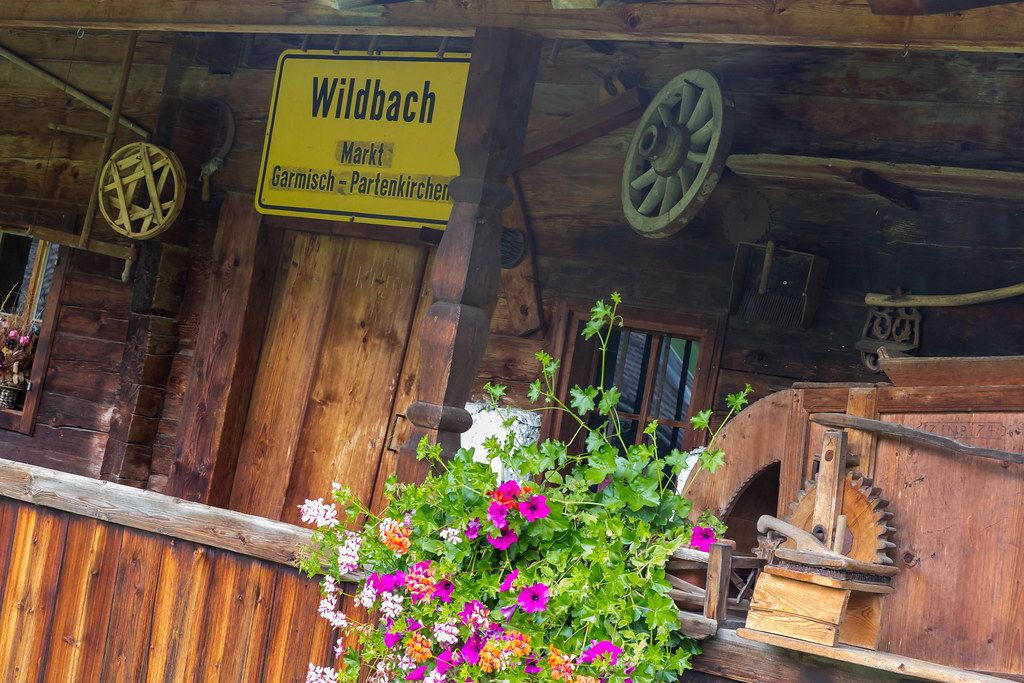 Hölzernes Gebäude mit Blumen und dem Schild "Wildbach - Markt - Garmisch - Partenkirchen"