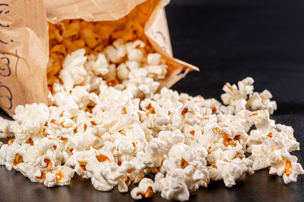 Homemade fresh popcorn with paper package on black