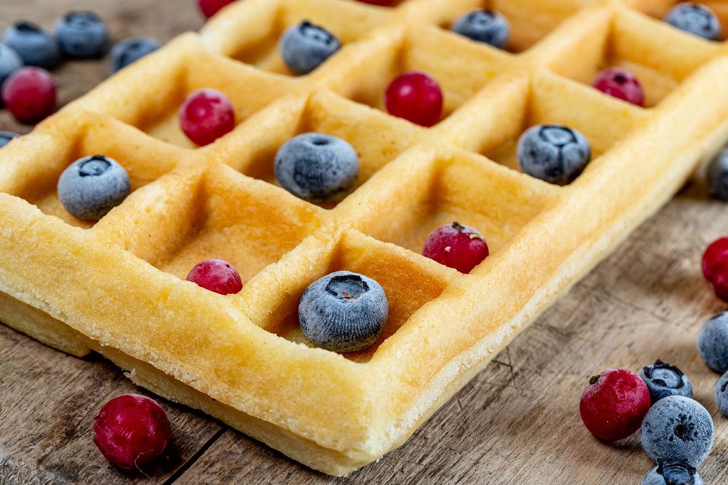Homemade waffles with berries on wooden background, close up