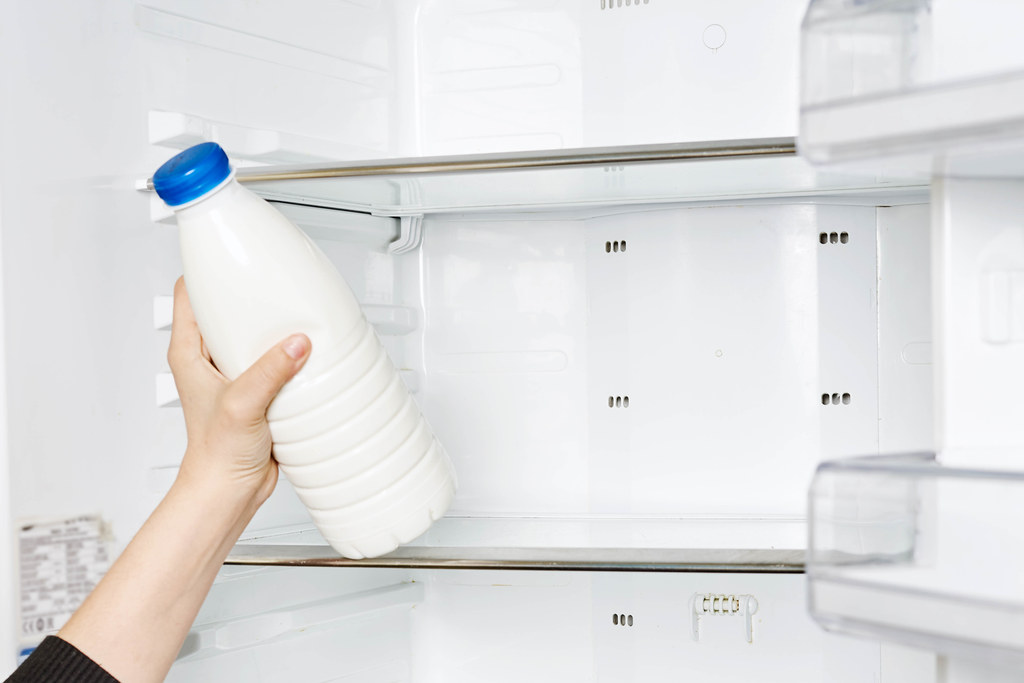 Housewife putting a bottle of yogurt into the refrigerator