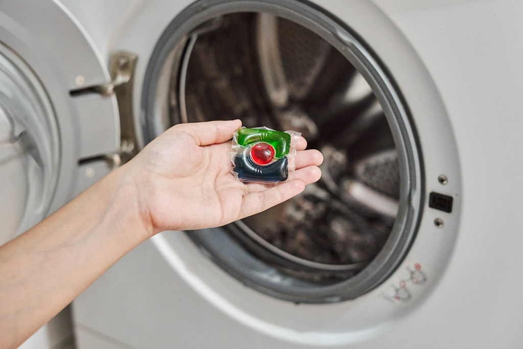 Housewife putting liquid capsules into the load of washing machine