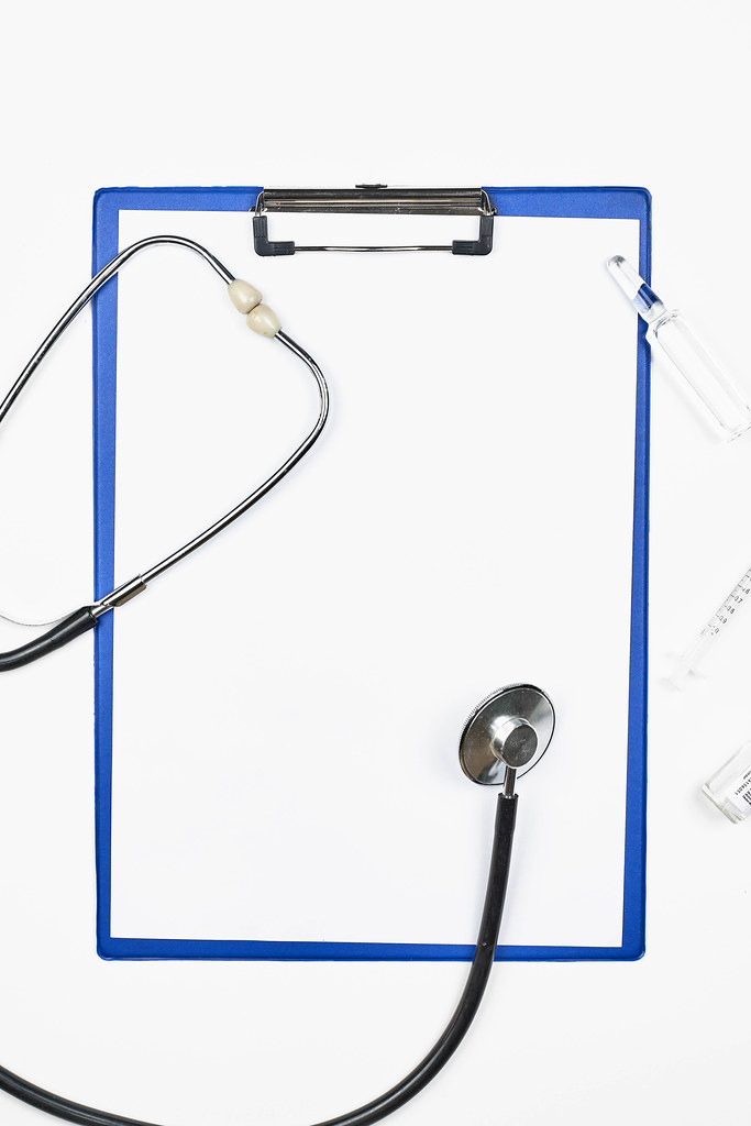 Klemmbrett mit Stethoskop, Spritze und Ampulle mit Platz für Text vor weißem Hintergrund