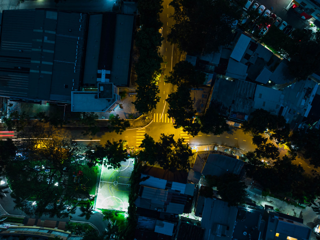 Long Exposure Top View Drone Photo of an Intersection in a local Neigborhood with Houses, Trees and a Football Field in District 4 in Ho Chi Minh City, Vietnam