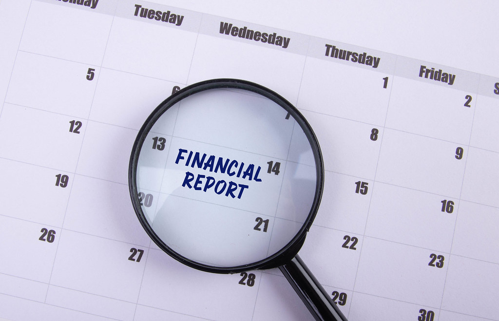 Magnifying glass with Financial Report text on the calendar