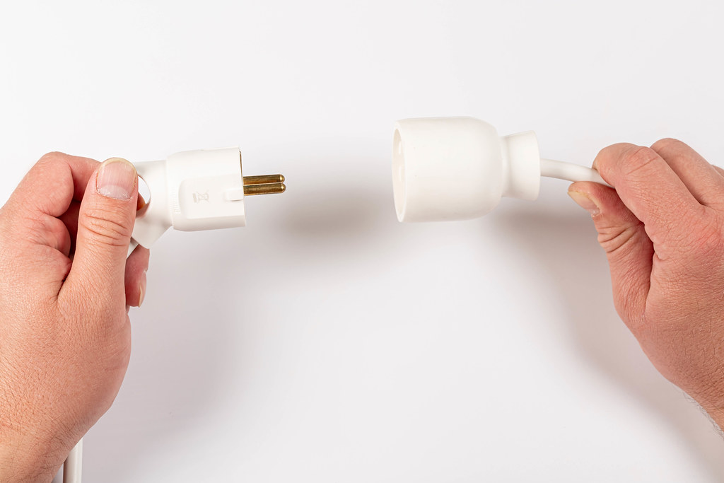 Male hand puts plug in the socket, white background