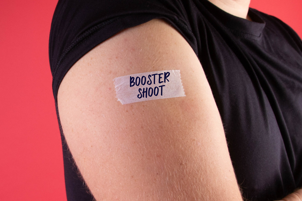 Man shows his sleeve with a bandage and Booster Shoot text