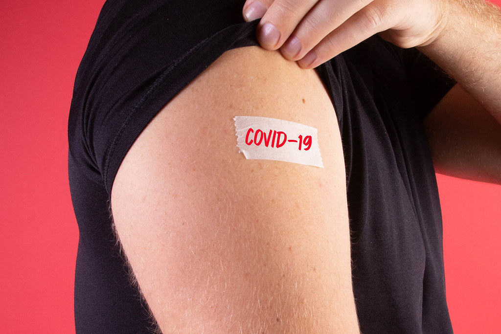 Man shows his sleeve with a bandage and Covid-19 text
