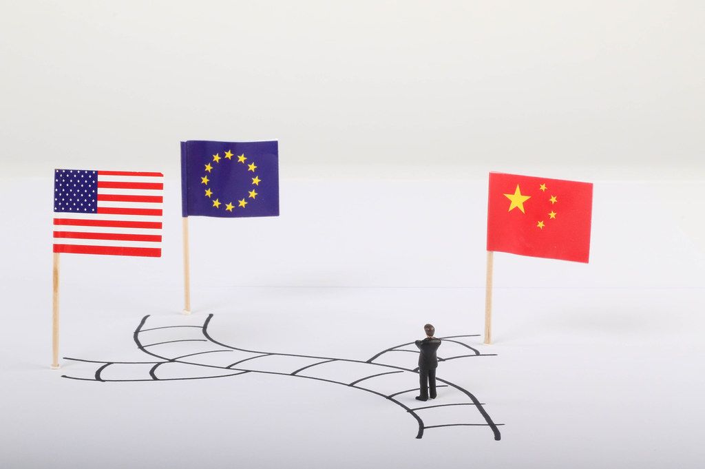Man standing on path with flags of USA, European Union and China