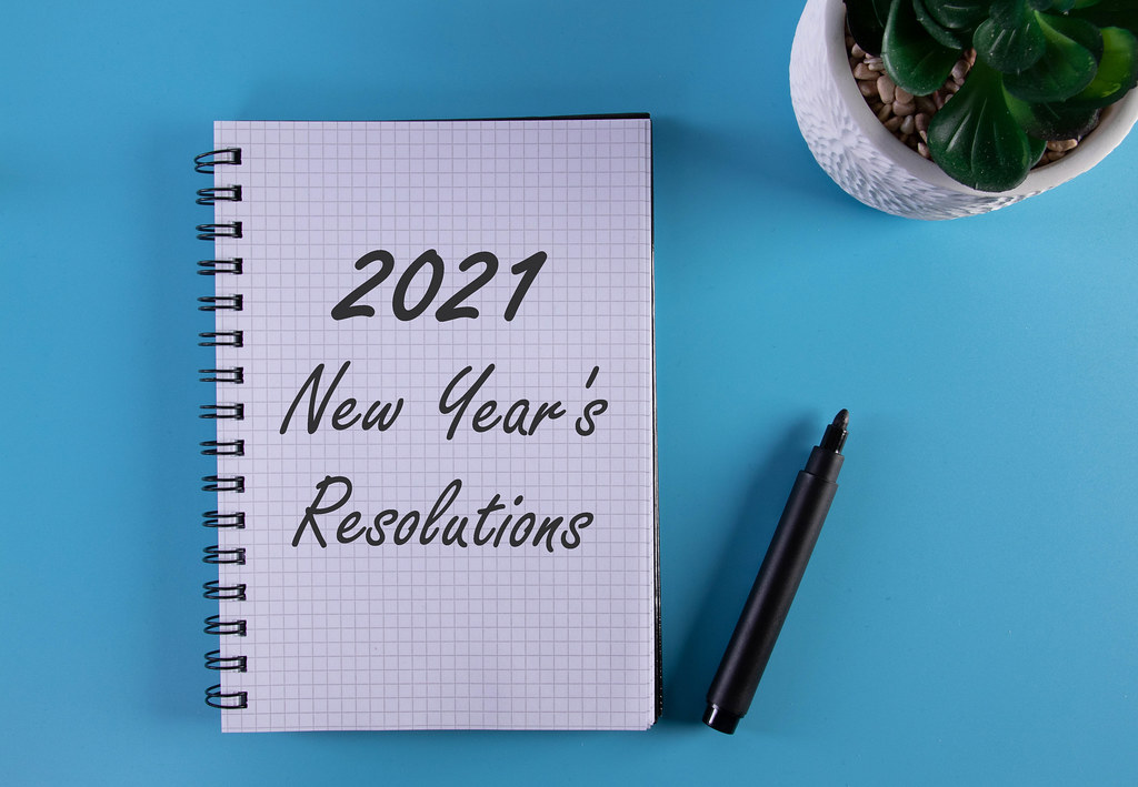 Marker and notebook with 2021 New Year's Resolutions on blue background