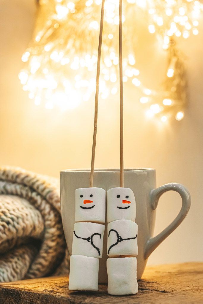 Marshmallow snowmen with a cup and beautiful bokeh of glowing garlands