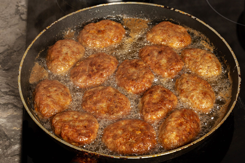 Meat cutlets are fried in a frying pan
