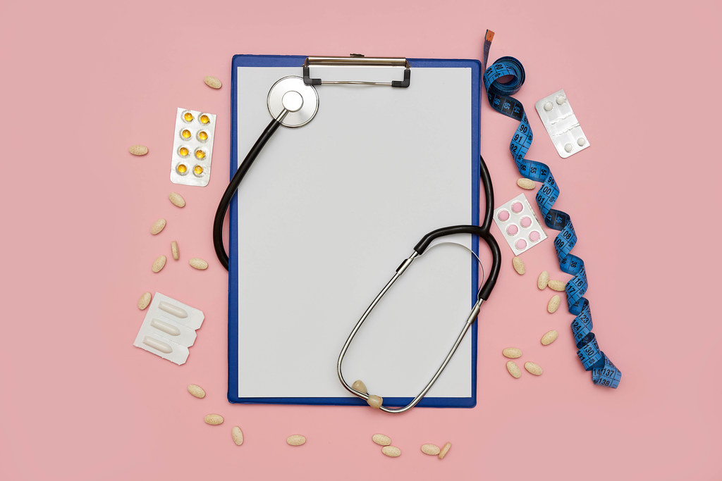 Medical background with stethoscope, medical pills and measuring tape