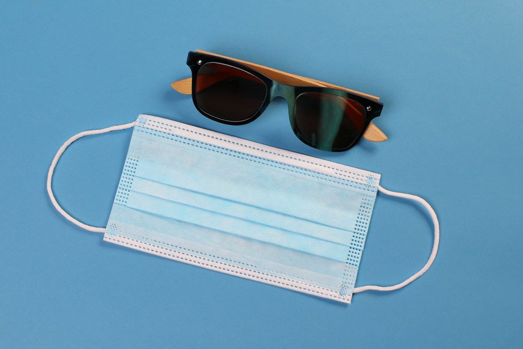 Medical face mask with sunglasses on blue background