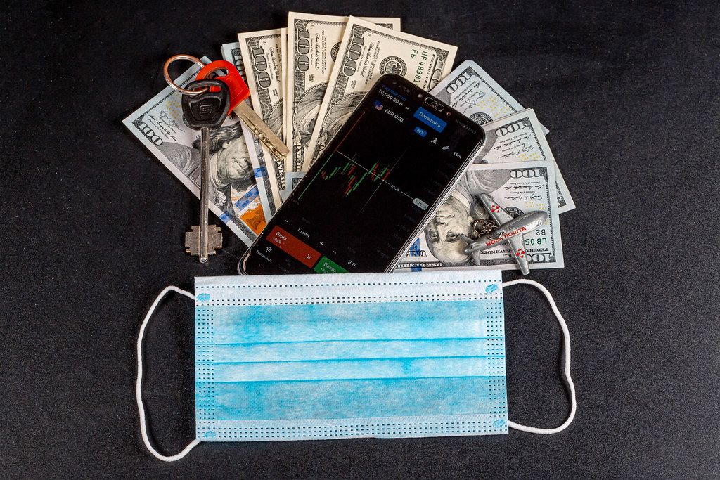 Medical mask with cash and smartphone on black background