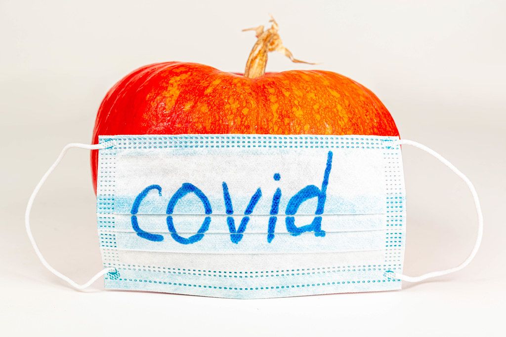 Medical mask with the inscription Covid and orange pumpkin on a white background