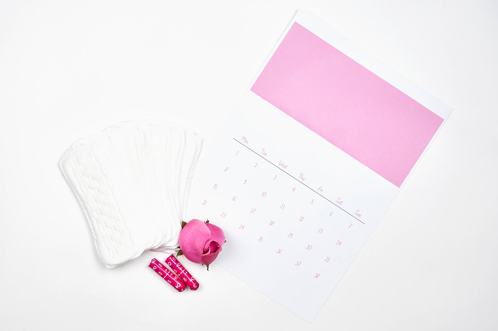 Menstrual pads on menstruation period calendar with rose flowers