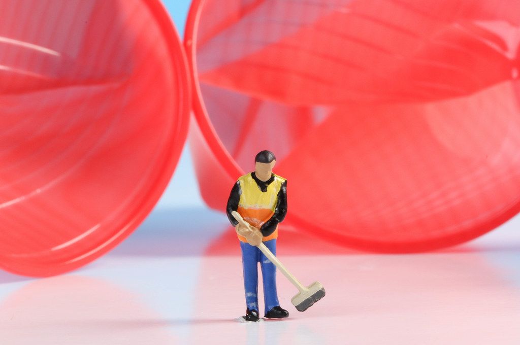 Miniature cleaning worker with empty red plastic cups