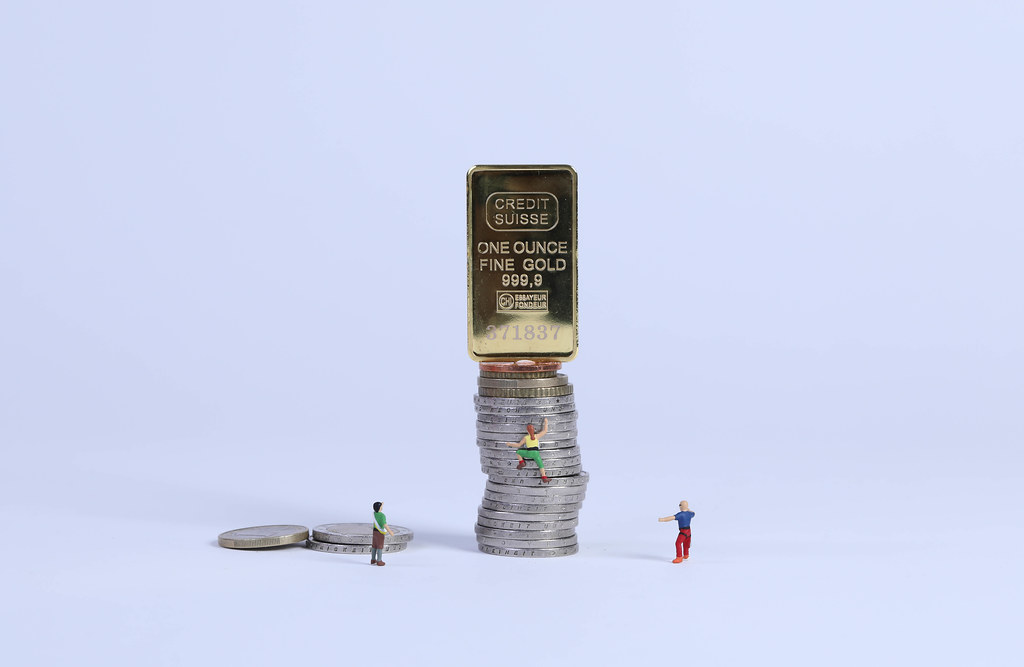 Miniature climber climbing on coin stack to golden brick