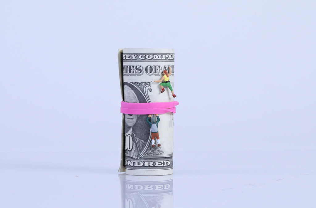 Miniature climbers on money roll on white background