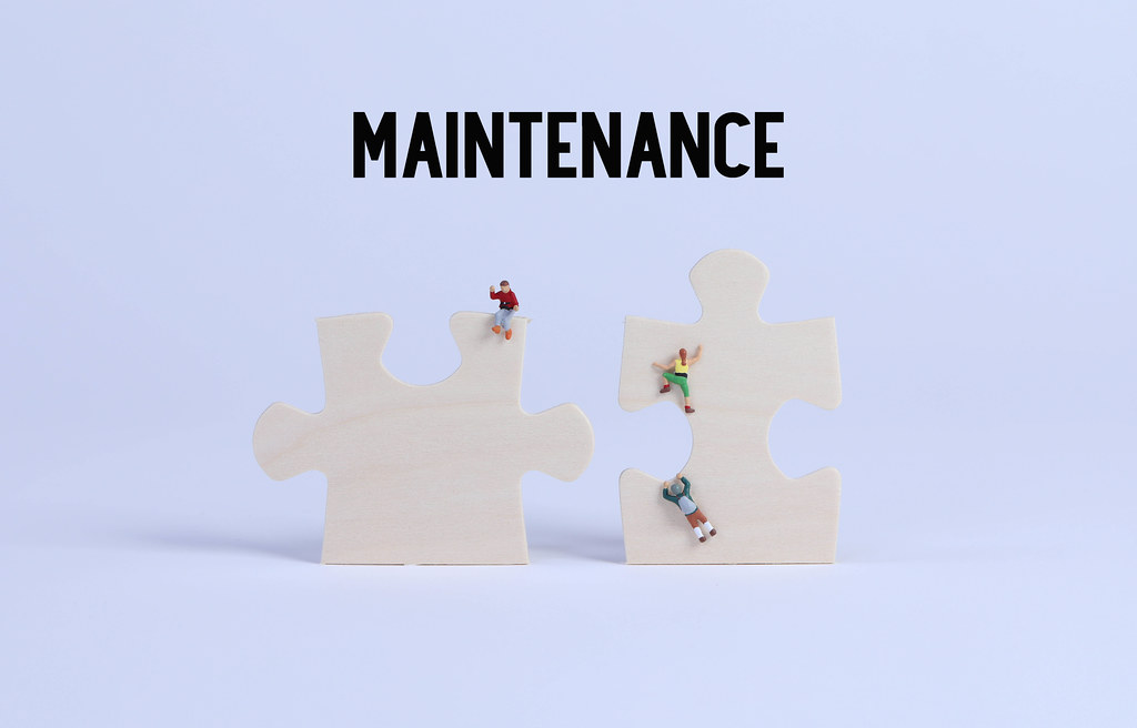 Miniature climbers on puzzle pieces with Maintenance text