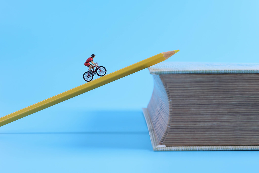 Miniature cyclist riding on a pen on a book