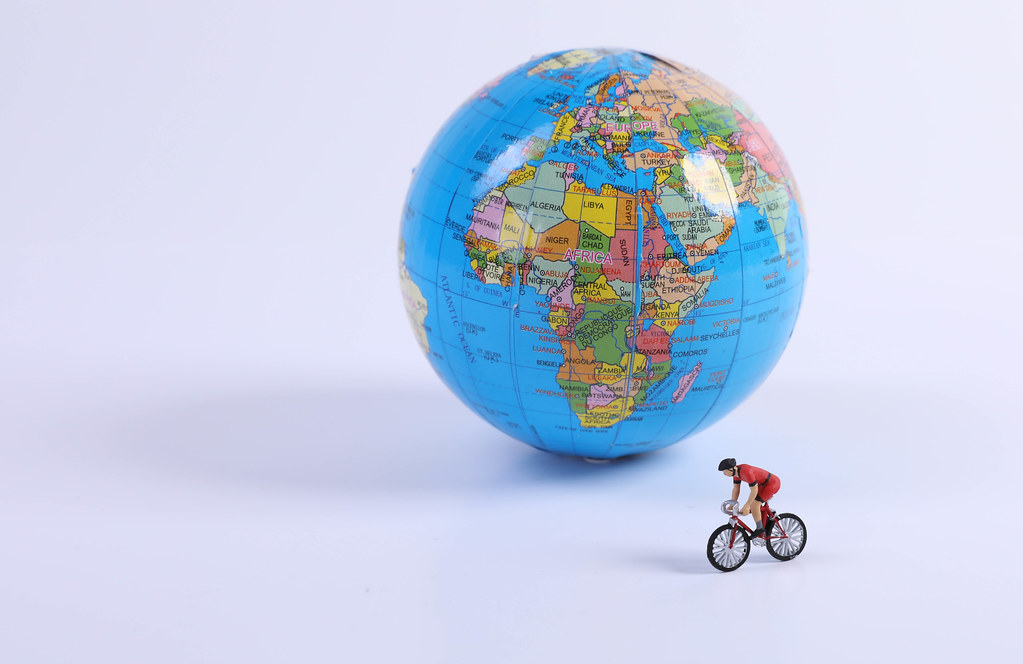 Miniature figure ride bicycle in front of globe