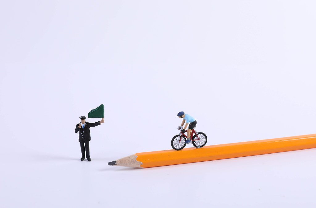 Miniature Figure Ride Bicycle on pen and man waving a green flag