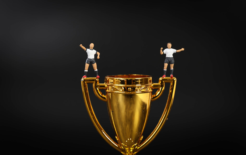 Miniature football players on golden trophy