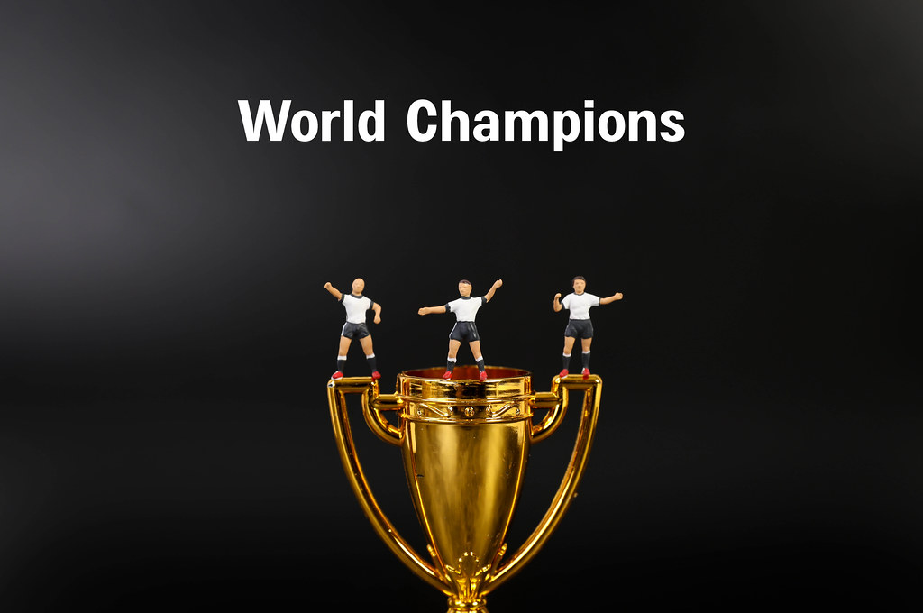 Miniature football players with golden trophy and World Champions text