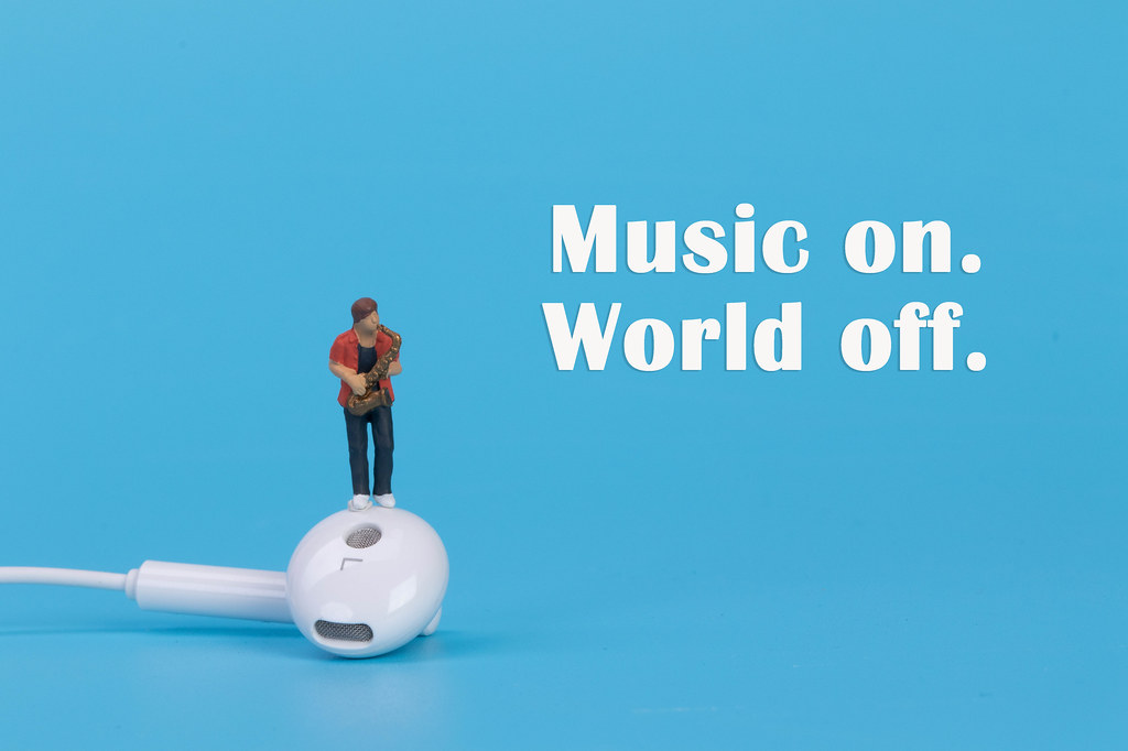 Miniature musician with earbud and Music on World off text