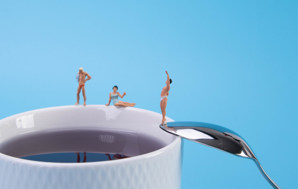Miniature people relaxing around the coffee cup