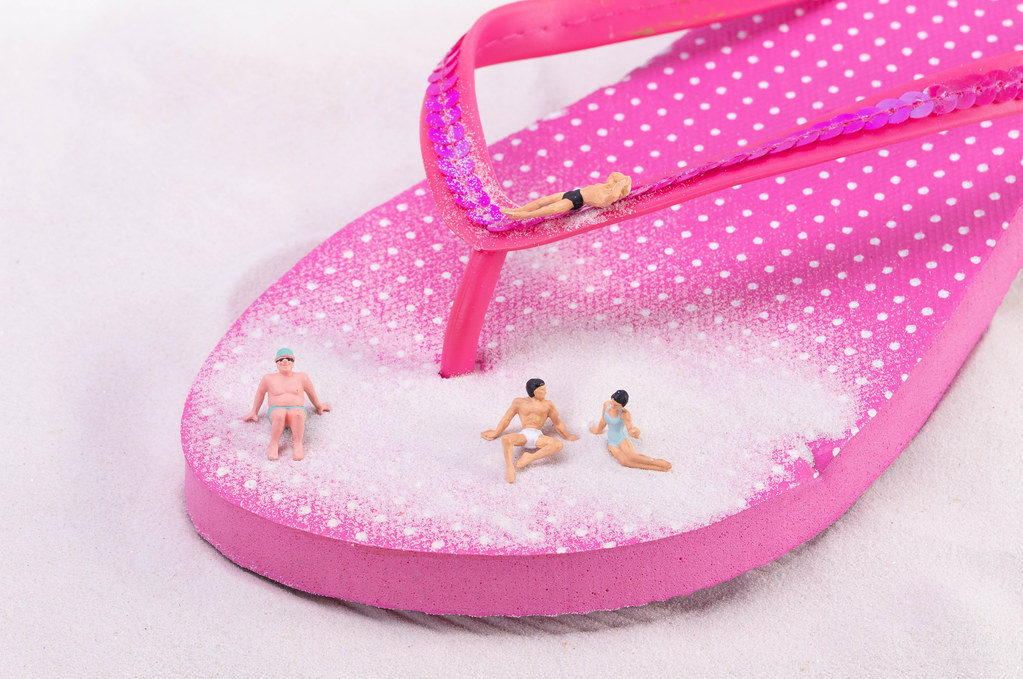 Miniature people relaxing on flip flops shoe